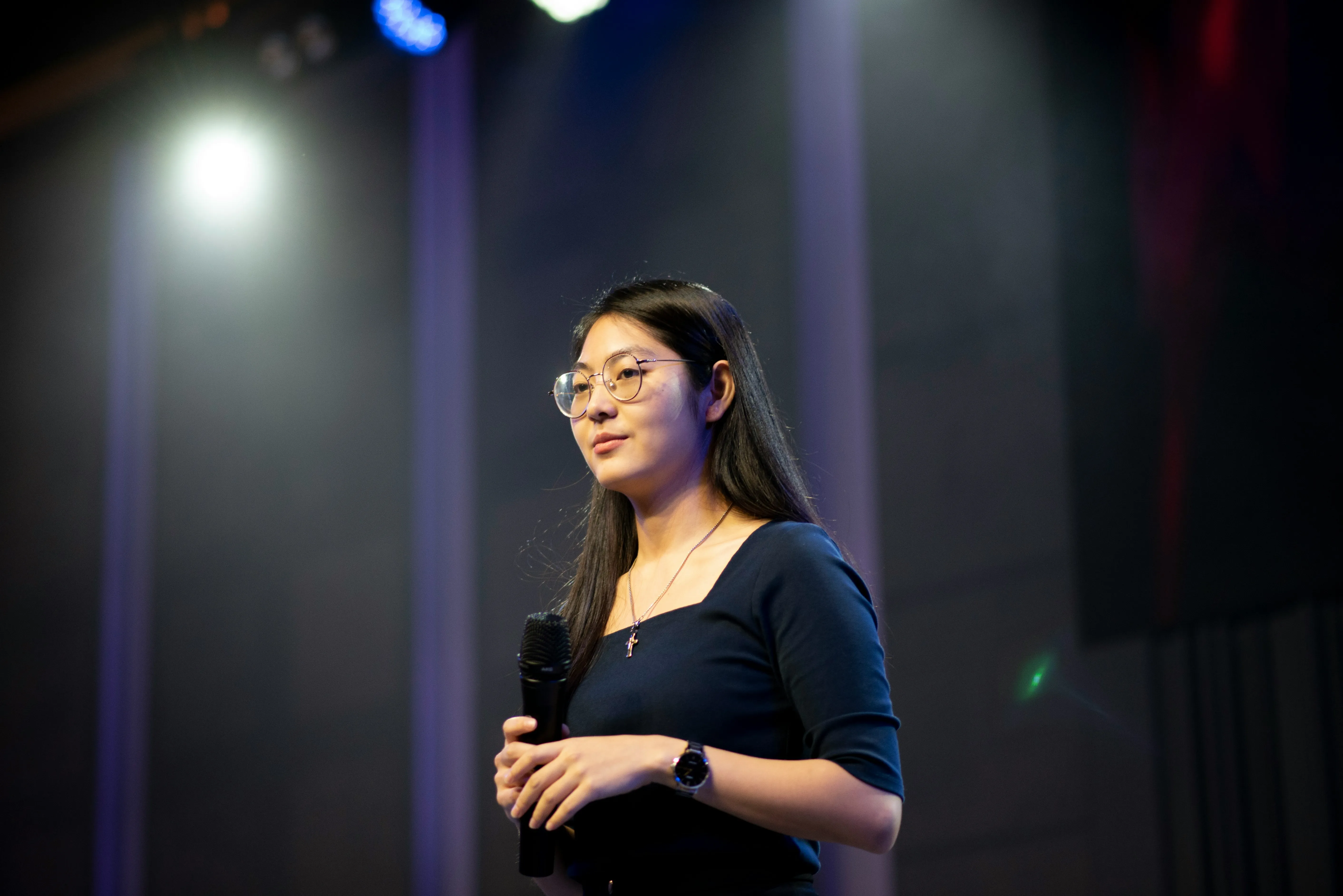 Student confidently speaking on stage after learning debating and public speaking